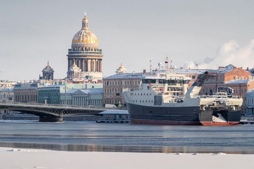 The panoramic view of the winter city Saint-Petersburg, big ship moored near Blagoveshchensky bridge, Isaac cathedral on background. High quality photo