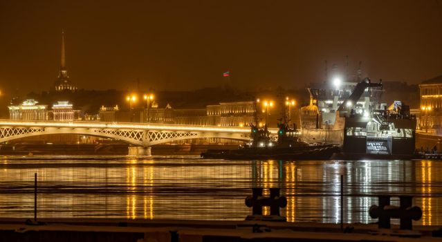 Russia, St.Petersburg, 02 February 2021: The panoramic photo of the winter night city with picturesque reflection on water, big ship moored near Blagoveshchensky bridge, Admiralty building. High quality photo