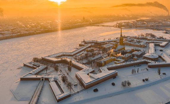 Drone point of view of winter St. Petersburg at sunset, frozen Neva river, steam over city, Peter and Paul fortress, car traffic on Trinity bridge, rostral columns, Palace drawbridge, panoramic view. High quality photo