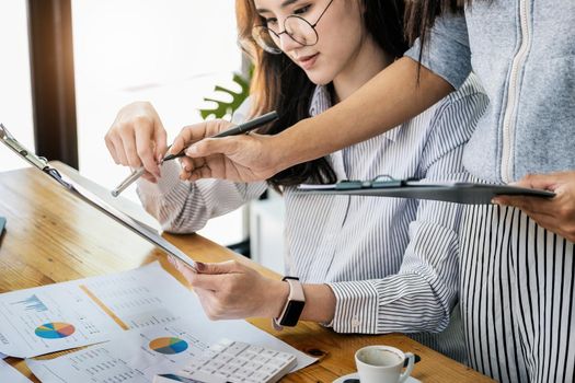 Businesswomen and colleagues are using budget document to calculate last quarter earnings of the year to plan financial investments for the coming year