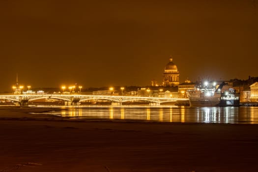 The panoramic footage of the winter night city Saint-Petersburg with picturesque reflection on water, big ship moored near Blagoveshchensky bridge or lieutenant Schmidt, Isaac cathedral on background. High quality photo