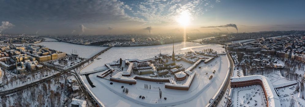 Drone point of view of winter St. Petersburg at sunset, frozen Neva river, steam over city, Peter and Paul fortress, car traffic on Trinity bridge, rostral columns, Palace drawbridge, panoramic view. High quality photo