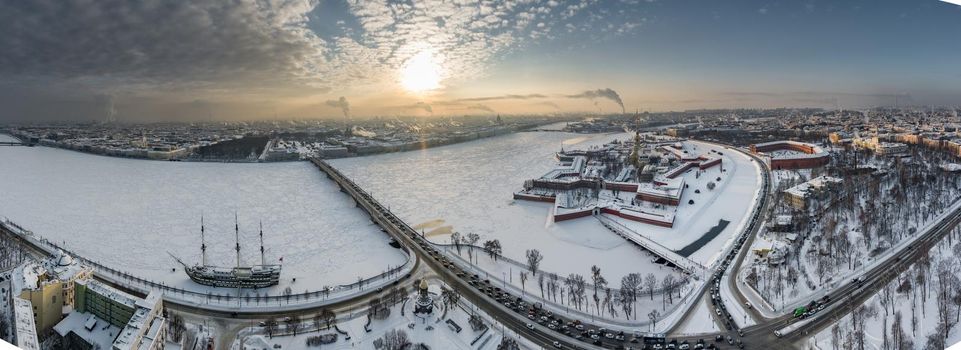 Drone point of view of winter St. Petersburg at sunset, frozen Neva river, steam over city, Peter and Paul fortress, car traffic on Trinity bridge, rostral columns, Palace drawbridge, panoramic view. High quality photo