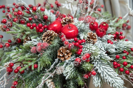 Winter bouquet of snow-covered spruce branches and cones with red berries of rowan and apples, small pomegranates. High quality photo