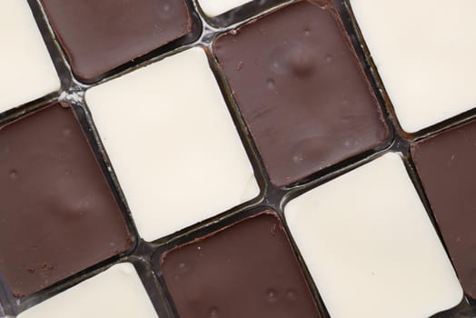 dark and white chocolate in a box on gray background .