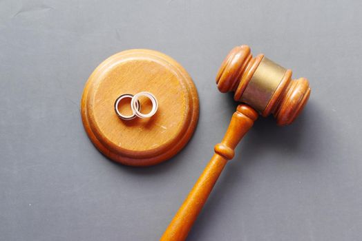 Divorce concept with gavel and wedding rings on table