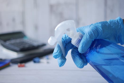 hand in blue rubber gloves holding spray bottle with copy space, top view