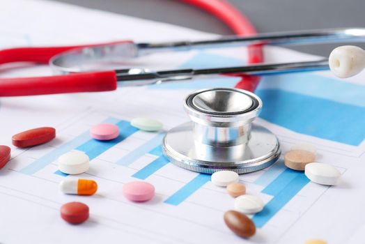 stethoscope , medical pills and financial data on table .