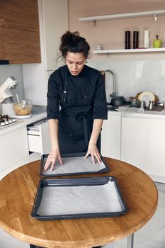 smiley woman is preparing tasty sweet dishes at light minimalistic kitchen