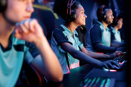 Selective focus on African female cybersport player participating in online video games competition with blurred team members on background