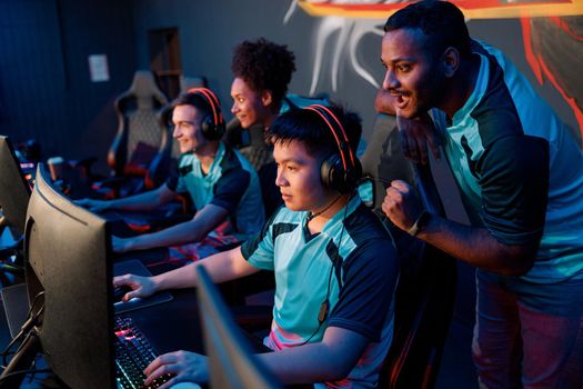 Cheerful African male cybersport gamer cheering his teammate while challenging difficult video game competition event in gaming club