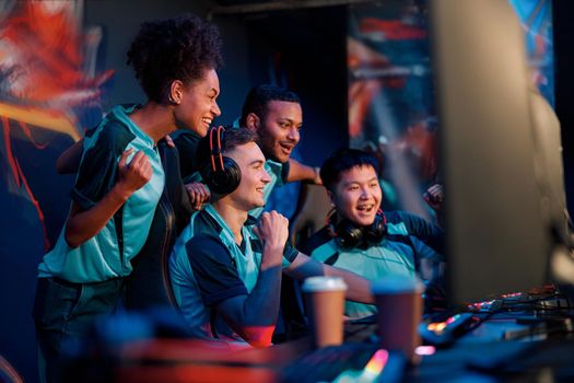 Side view of excited professional cyber gamers team celebrating success while participating in esports tournament in gaming club