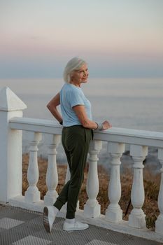 Active senior sportswoman living healthy lifestyle while exercising at coastal destination at morning sunrise