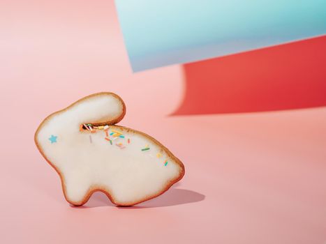 Easter bunny cookie on pink and blue paper pastel background with shadows. Happy Easter Day concept. Minimal Easter concept. Copy space for text. Easter cooking baking background.