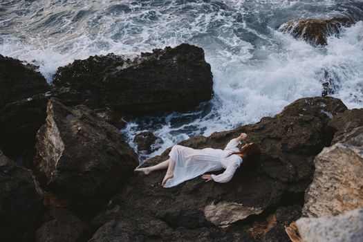 Barefoot woman in white wedding dress on sea shore wet hair view from above. High quality photo