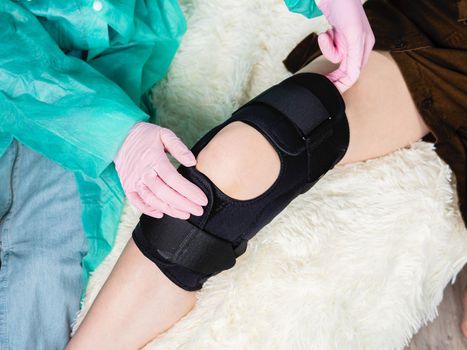 Close-up of a female physiotherapist applying a splint to the knee joint. Leg injury