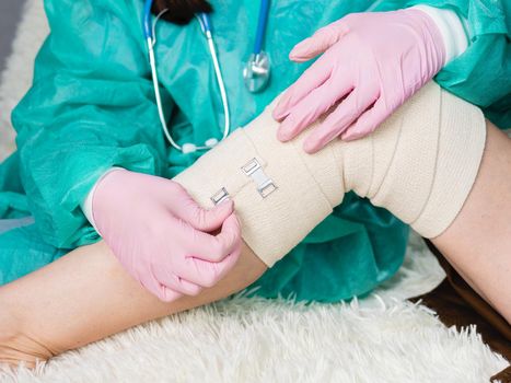 The doctor puts an elastic bandage on the patient's knee. Joint replacement surgery