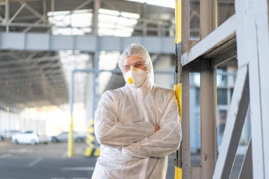 COVID-19 coronavirus doctor standing hospital parking dressed white protective overalls hazmat suit. Infectious disease pandemic medical worker front line, outbreak. Male medical worker medium shoot