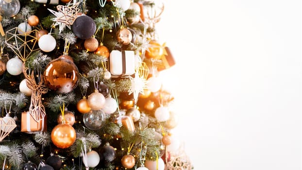 Christmas tree close up standing white wall background decorated white black gold color with light garland. Christmas decoration with copy space