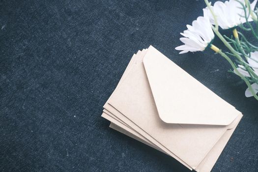 stack of envelope and flower on black background .
