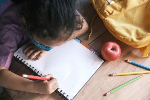 6 year old child girl hand writing on notepad sitting on a chair