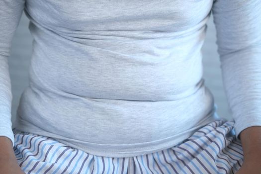 man's hand holding excessive belly fat, overweight concept.