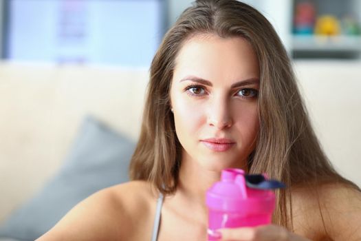 Portrait of woman athlete with pink plastic water bottle. Healthy lifestyle concept