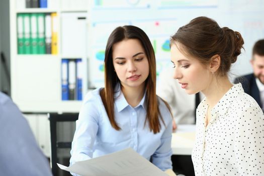 Two young women studying documents in office. Business education concept