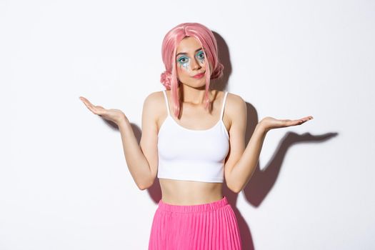 Portrait of clueless beautiful young woman shrugging, standing unaware in halloween costume with pink hair and bright makeup.