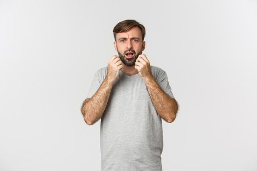 Portrait of horrified and shocked man grimacing, standing anxious over white background.