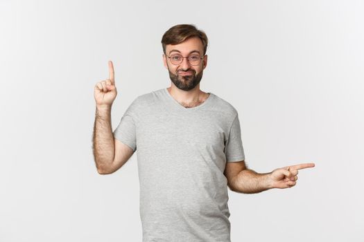 Indecisive bearded guy with beard, pointing up and right, showing two variants, making choice, standing over white background.