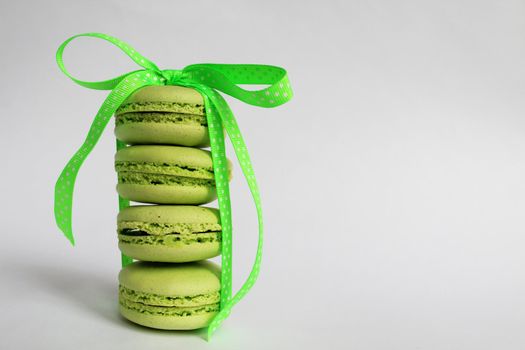 Green macaroon cakes with a light green ribbon on a white background. Nice design for any purpose. White background. Surprise for the holiday.
