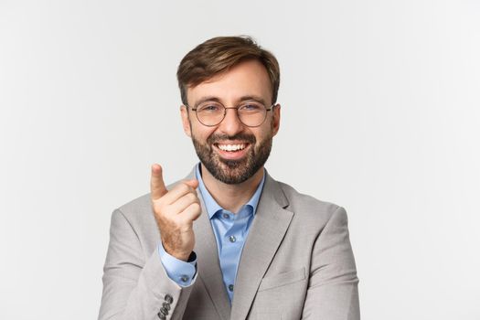 Close-up of handsome businessman with beard, wearing gray suit and glasses, praising good point, smiling pleased, standing over white background.