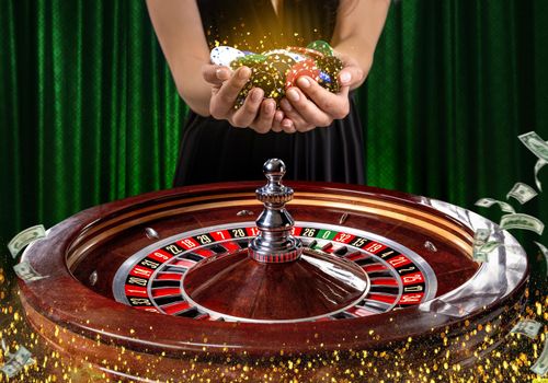 Collage of casino images with a close-up vibrant image of multicolored casino roulette table with poker chips in woman hands. Green background with golden sparks