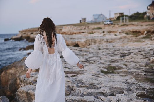 woman with wet hair in white dress stony coast. High quality photo