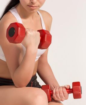 Young beautiful sportswoman doing fitness exercise with dumbbells, at studio shot. Health, beauty and fitness concept.