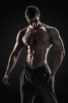 Sporty and healthy man posing and showing his perfect boddy on black background