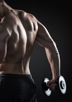 Muscular fitness man with dumbbells on black background, rear view. Close-up