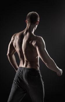 Stunning muscular man fitness model torso showing muscles back and shoulders on black background