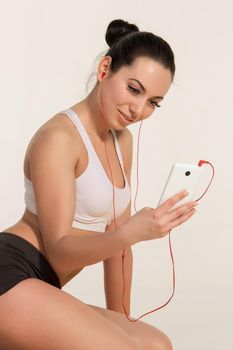 Brunette with fit body on yoga mat. girl with phone and headphones. Healthy lifestyle and sports concept.