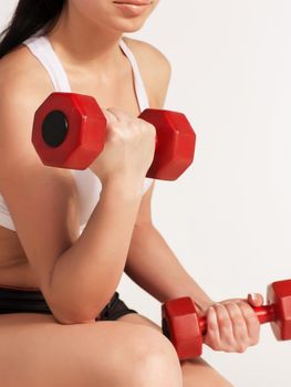 Young beautiful sportswoman doing fitness exercise with dumbbells, at studio shot. Health, beauty and fitness concept.