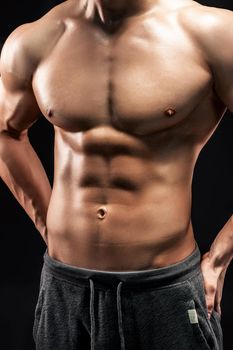 Close-up of a power fitness man. Strong man with muscles and biceps on black background.