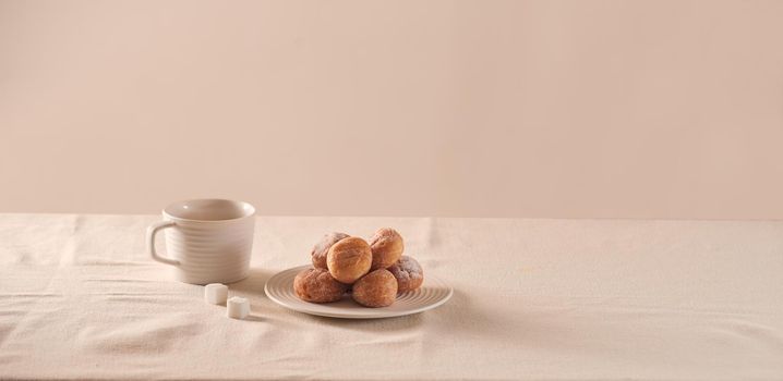 Donuts with sugar on plate and coffee cup on white background