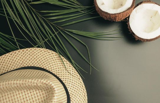 Summer composition with neon lights. Tropical palm leaves, hat, coconut on a dark background. The concept of the summer season, parties and heat. Flat lay, top view, copy space