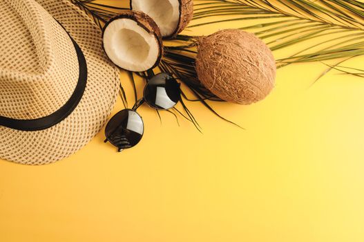 Summer composition. Tropical palm leaves, hat, glasses and broken coconut on a sandy background. The concept of the summer season, parties and heat. Flat lay, top view, copy space