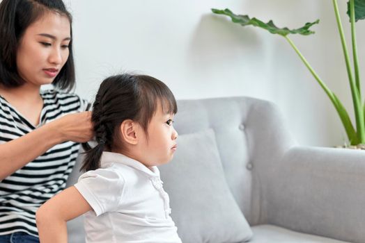 mother braiding hair of her daughter