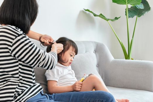 mother braiding hair of her daughter