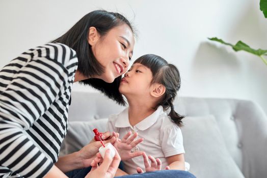 Mother and daughter having fun painting fingernails, family time concept