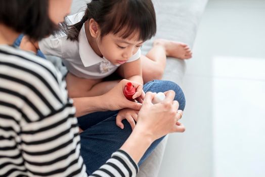 Mother and daughter having fun painting fingernails, family time concept