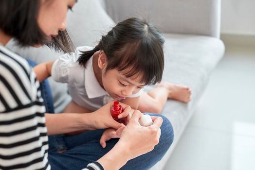 Mother and daughter having fun painting fingernails, family time concept